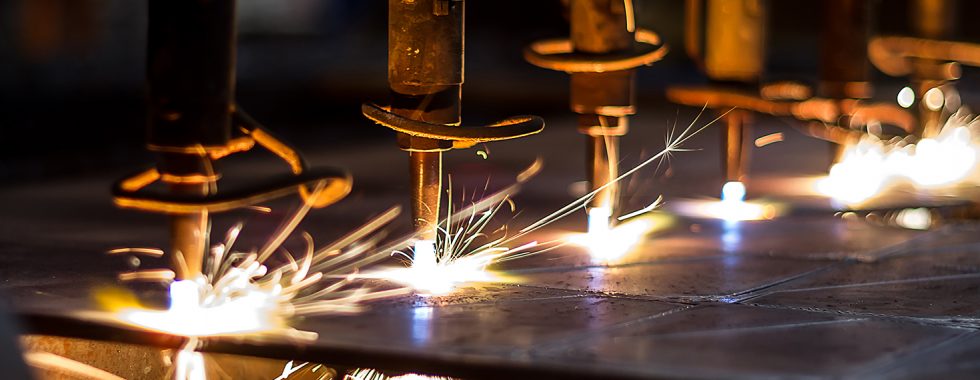 Closeup shot of a CNC machine processing a piece of metal. There are three water streams splashing the object to cool it down.